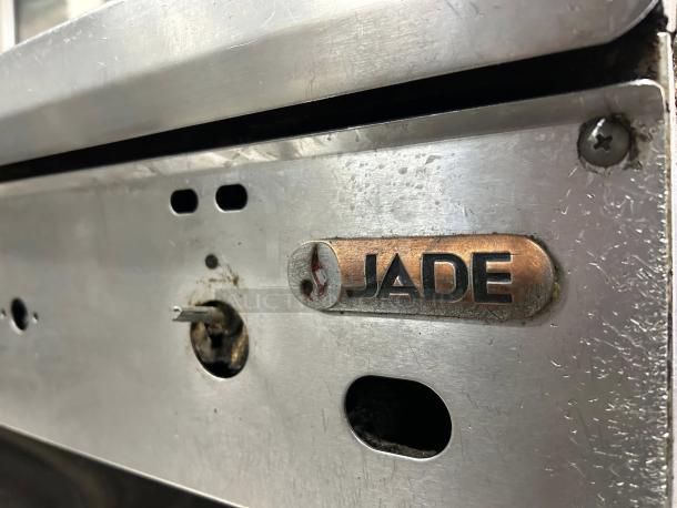 Jade Range 48" Gas Griddle close-up, showing brand logo. Steel panel with vent openings and control hole, in excellent condition.