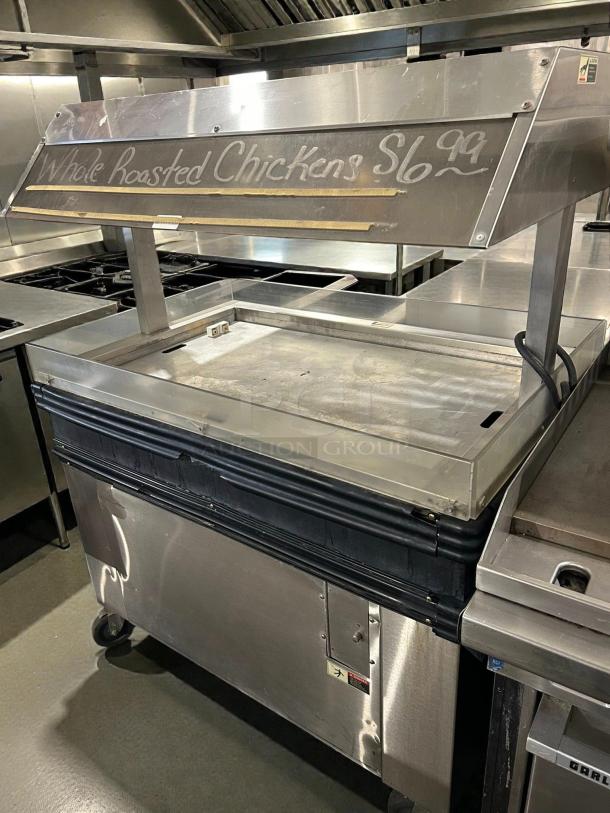 BKI MM-4 heated merchandiser display in stainless steel, tested and working, with a sign for whole roasted chickens.