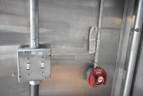 Electrical and fire safety controls inside a 2021 Cruising Kitchens fast food trailer. Includes labeled switches and a fire pull station.