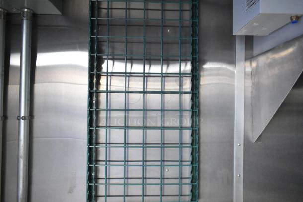 Interior view of a brand new Cruising Kitchens fast food trailer, showcasing industrial shelving and stainless steel surfaces.