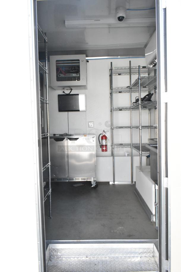 Inside view of a brand new 2021 Nationwide 24' food trailer with stainless steel equipment, wire shelving, and security system.