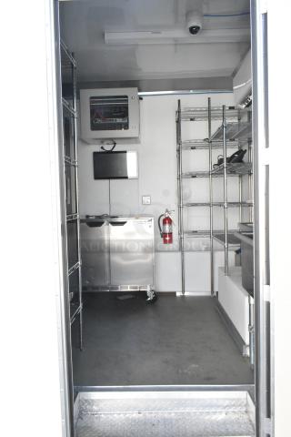 Inside view of a brand new 2021 Nationwide 24' food trailer with stainless steel equipment, wire shelving, and security system.