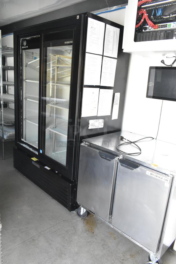 Fully equipped retail trailer interior with Beverage Air cooler, freezer merchandisers, shelving, and security system. Brand new condition.