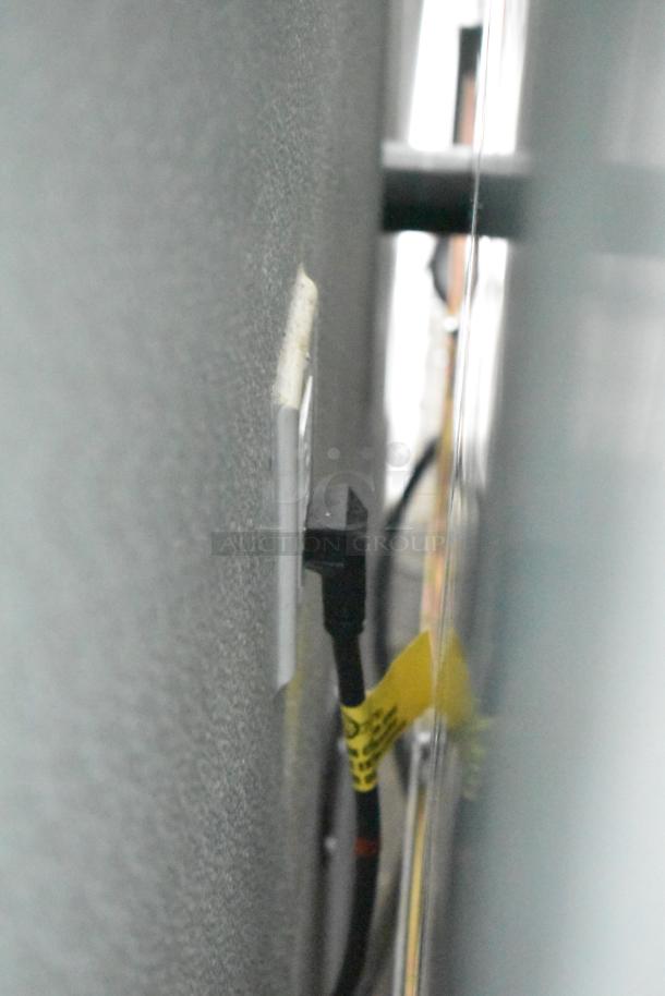 Close-up view of a power outlet with a plugged-in cable, featuring a yellow tag possibly indicating safety or equipment details.