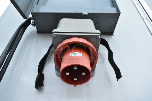 Close-up of industrial power connector on Nationwide 24' trailer, showing a red plug and attached label with specifications.