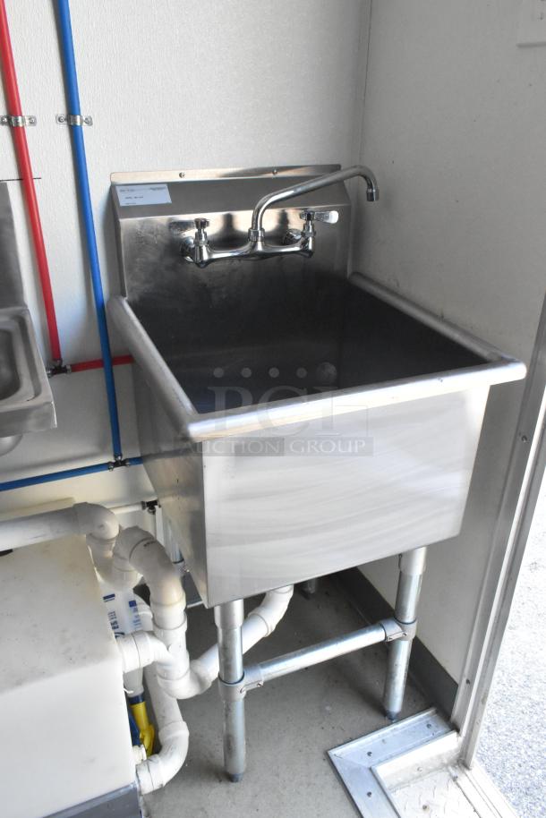 Stainless steel commercial sink with faucet in a retail food trailer setting, featuring visible plumbing and clean condition.