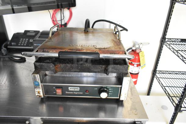 Waring Tostato Supremo panini press on a stainless steel counter, used condition, with temperature controls and visible wear.
