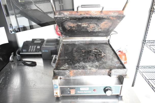 Waring Panini Press on stainless steel counter in retail trailer, visibly used. Includes POS system and phone nearby.
