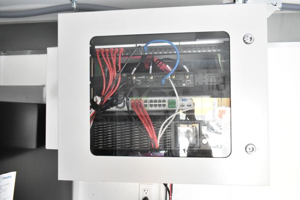 Network equipment cabinet with red and blue cables, switches, and routers inside the Nationwide retail trailer.