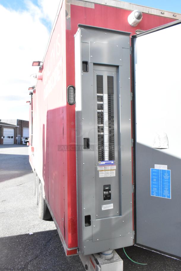 Electrical breaker panel installed on a red trailer exterior. Features multiple breakers and visible safety labels.
