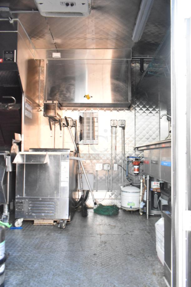 Commercial kitchen interior featuring stainless steel appliances and equipment, including a refrigerator and sink, in good condition.