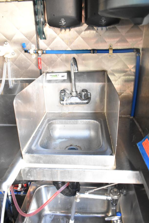 Commercial stainless steel sink with faucet and splash guards. Regency NSF label visible. Condition: used.