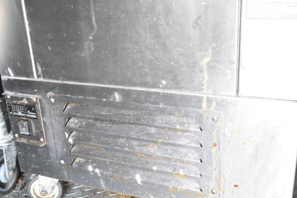 Industrial appliance with vented panel and control display. Visible wear with surface scratches and residue, mounted on wheels.