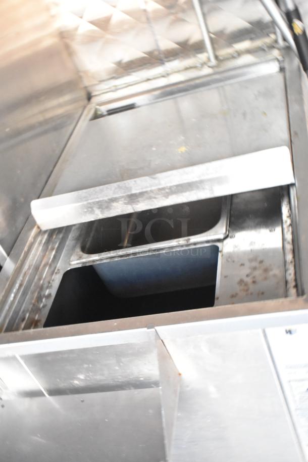 Stainless steel commercial kitchen sink with two compartments, mild wear and signs of use.