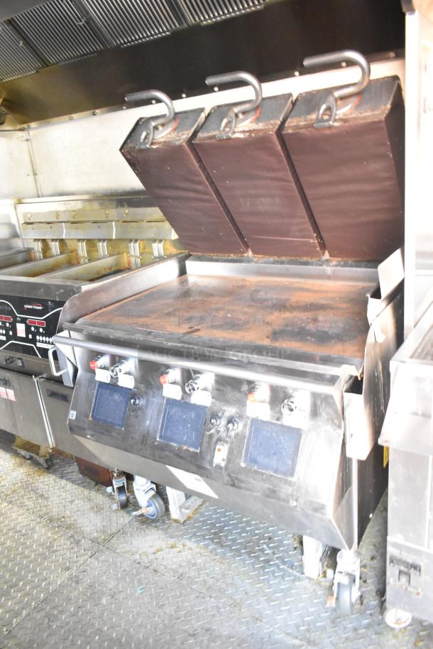 Commercial flat-top griddle with three press lids, digital controls, and portable design on wheels. Shows signs of wear.