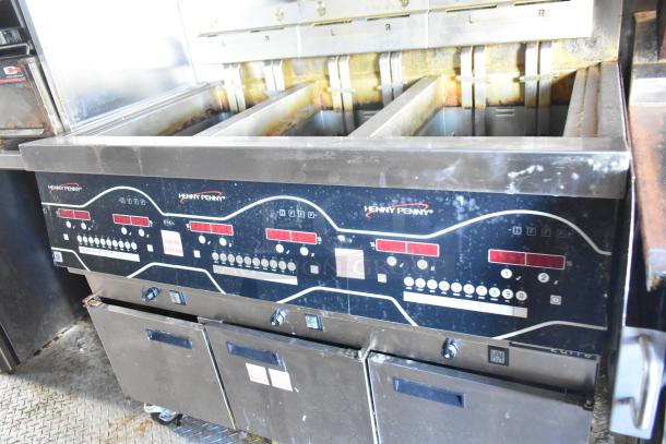 Henny Penny commercial fryer with multiple vats, digital controls, showing signs of wear, used in restaurant settings.