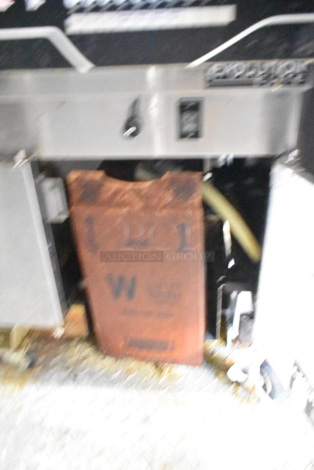 Blurry image of industrial equipment with stainless steel surfaces and a rusted component labeled with "W" and "1."