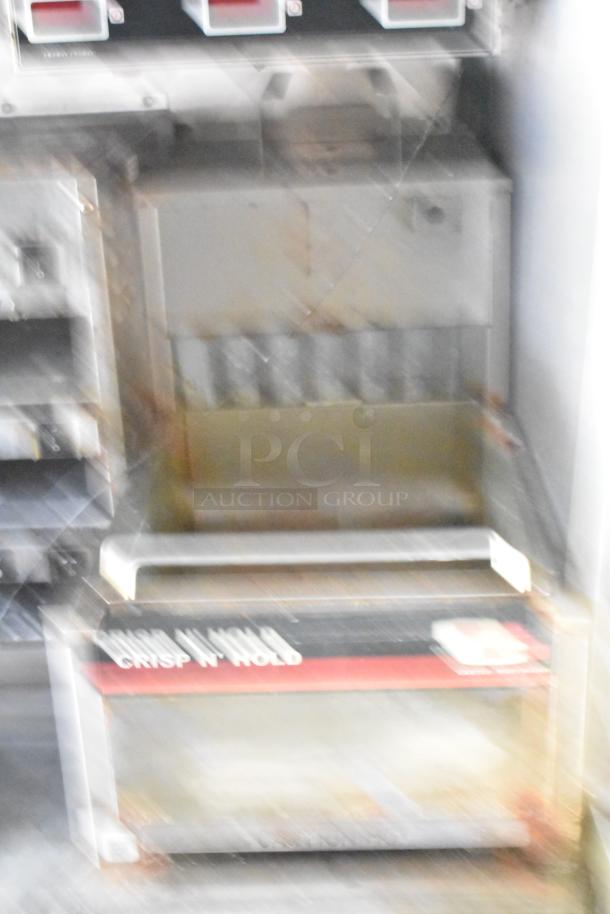 Industrial kitchen equipment with "CRISP N' HOLD" label, metallic exterior, shows signs of wear.