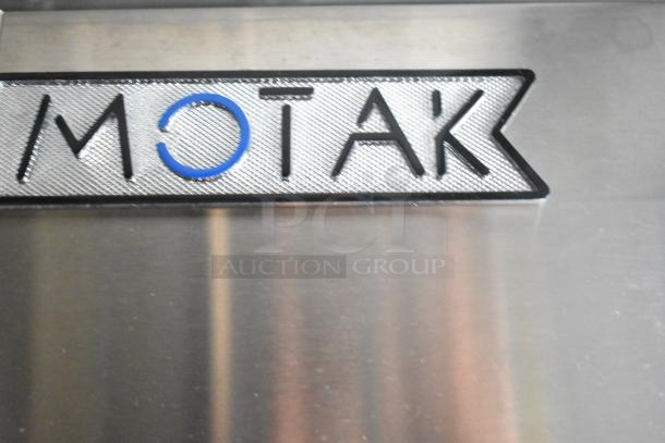 Motak metal plate logo on stainless steel surface, indicating brand identity.