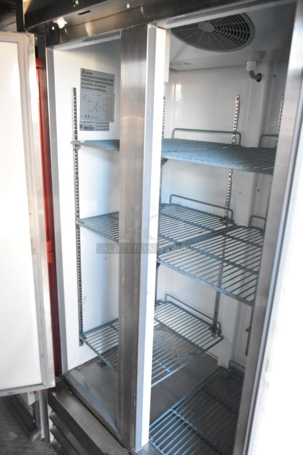 Commercial refrigerator with metal shelves and ventilation fan, in good condition, visible model label inside.