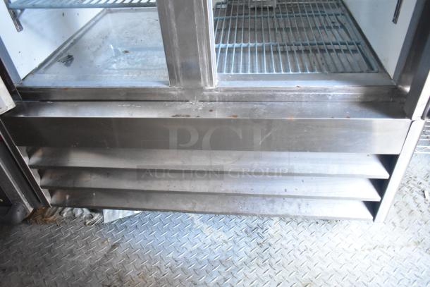 Stainless steel commercial refrigerator base with vented grille, showing minor rust and use wear. Suitable for restaurant use.