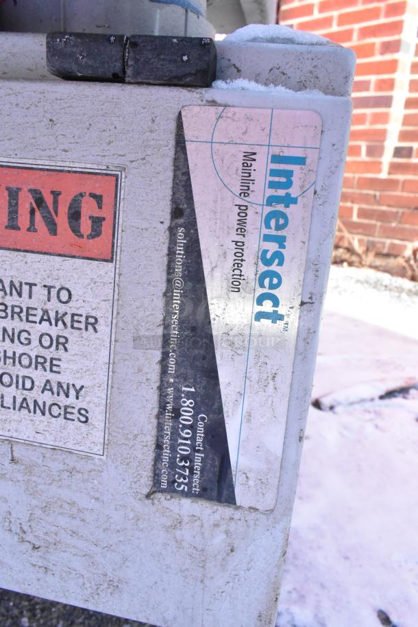 Weathered electrical box with "Intersect" sticker for mainline power protection; warning label partially visible.