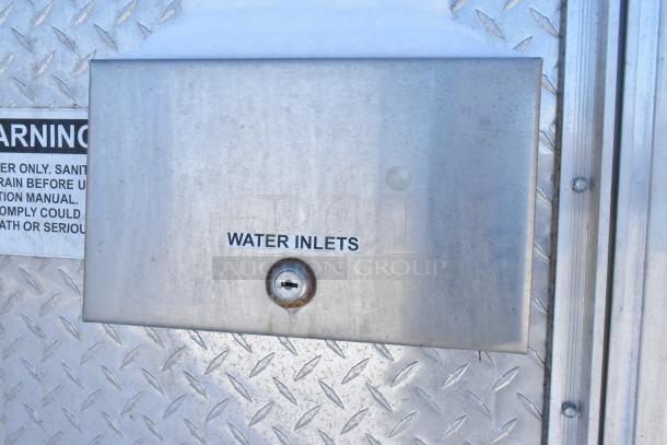 Close-up of the water inlets panel on a fast food trailer, featuring labeled metal cover and diamond plate surface.