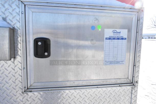 Side view of a Wendy's fast food trailer, showing diamond plate metal covering and a service record sticker.