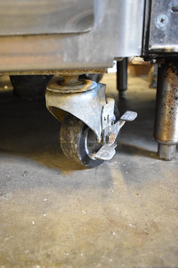 Close-up of a caster wheel on a 2021 Stoelting M202-209B00SIR stainless steel custard freezer; shows wear and rust.