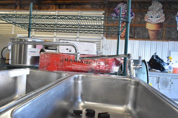 A stainless steel commercial kitchen with various equipment, including a Nemco soup warmer and a faucet.
