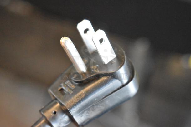 Close-up of a three-prong plug from the Scotsman UN1520AX-1A ice machine, showing intact prongs and a sturdy build.