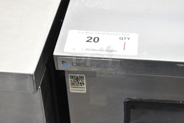 Delfield stainless steel single door undercounter cooler with commercial casters. Label shows 115V, 1 phase. Logo and QR code visible.