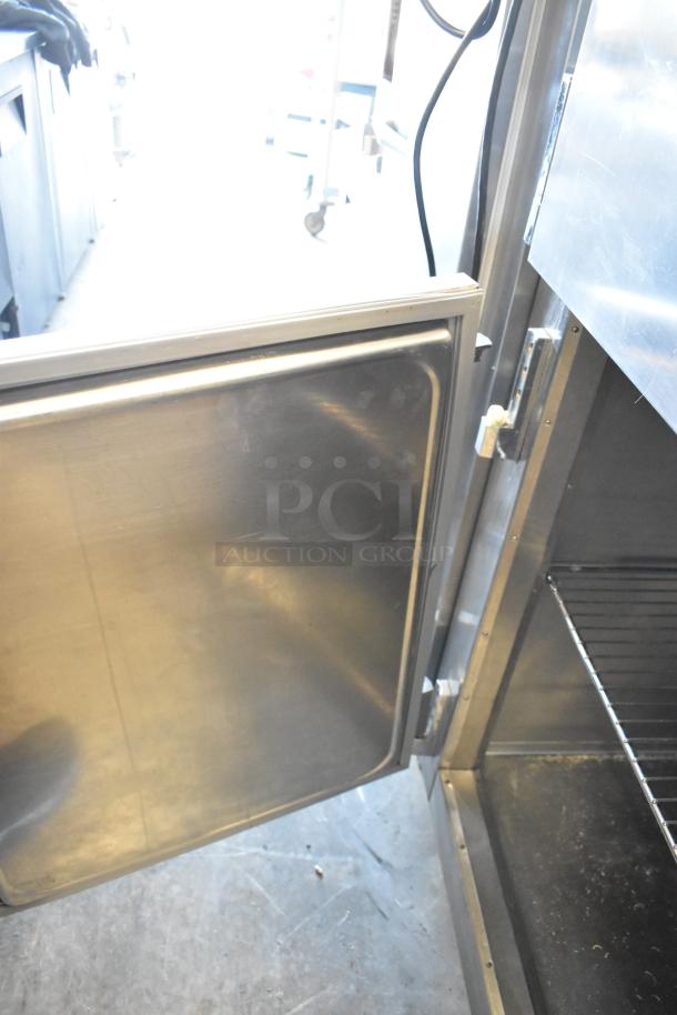 Traulsen RHT132WREHHS stainless steel reach-in cooler, 2 half-size doors, shelving, 115V, in used condition.