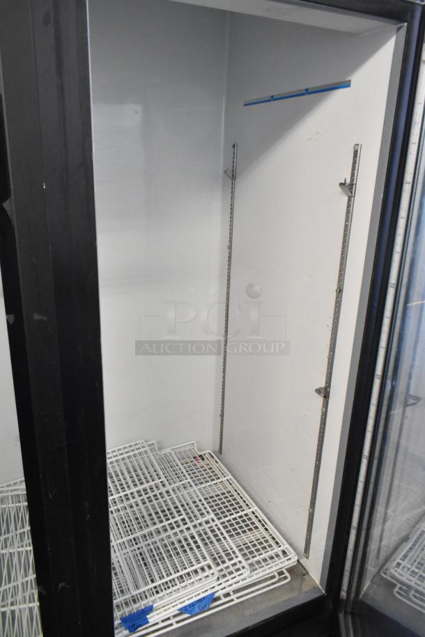 Central 69K-056 metal 3-door reach-in cooler merchandiser with poly coated racks, 115 volts, 1 phase, interior view.