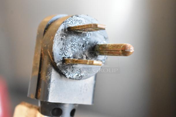 Close-up of a worn electrical plug with visible three prongs and some oxidation, possibly for the True TBB-4 cooler.