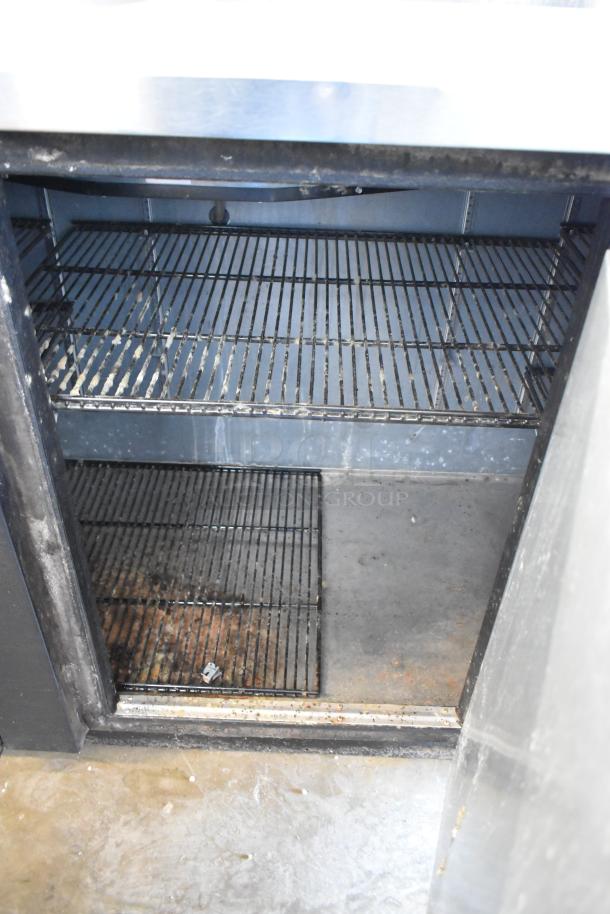 2017 True TBB-4 commercial back bar cooler, 3 doors, metal, condition shows wear, 115 volts, 1 phase, shelving visible.