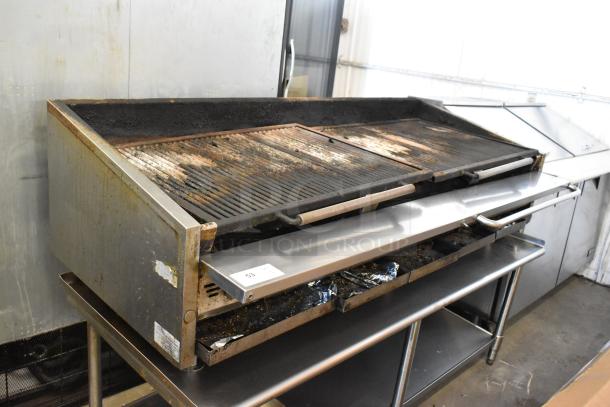 Stainless steel commercial countertop gas charbroiler grill on equipment stand, used condition, visible wear and residue.