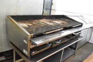 Stainless steel commercial countertop gas charbroiler grill on equipment stand, used condition, visible wear and residue.