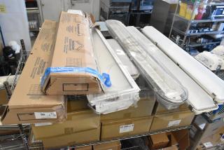 Seven light fixtures, including Lithonia Lighting GTL 4 40L GZ10 LP840, in new condition with packaging visible.