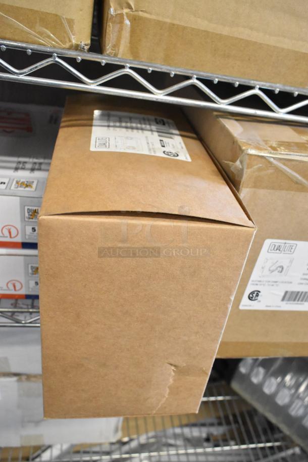 Boxes of Dual Lite LED emergency lights and exit signs, brand new with minor dents. Labels show brand and compliance info.