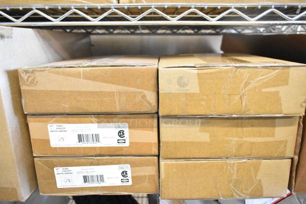 16 new boxes containing Dual Lite LED emergency lights, exit signs, and remote heads, some with minor dents. Labels indicate model EVHC2P, suitable for damp locations.