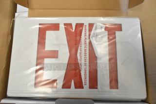 Box of 6 brand new scratch and dent exit signs, red lettering, in packaging. Tags warn of plastic suffocation risk.