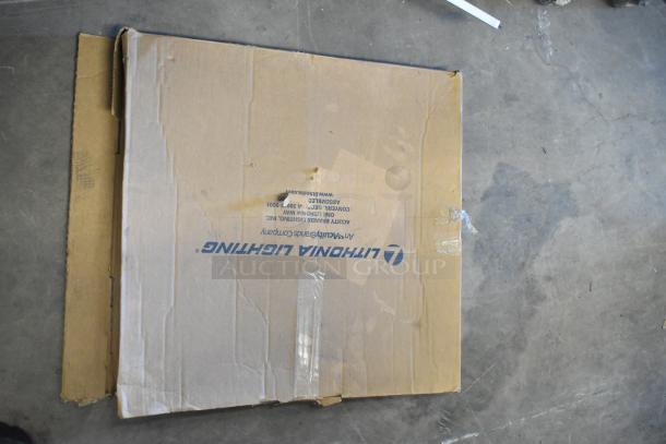 Cardboard box labeled "Lithonia Lighting" containing various fluorescent lights, including Banner WBL32C285PB. Box is scratched and taped.