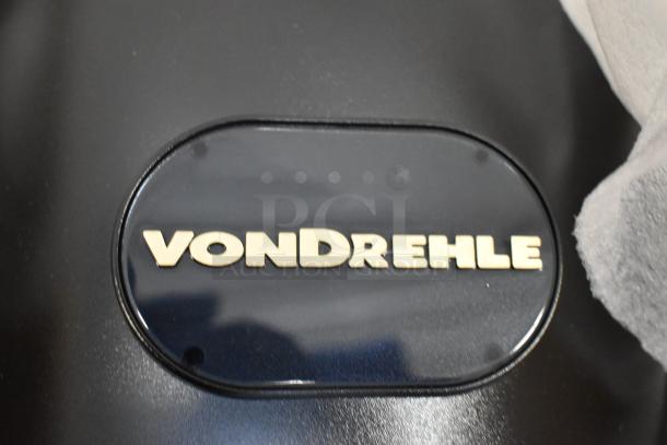 VonDrehle center pull towel dispenser, new with scratches and dents, black finish, brand logo visible.