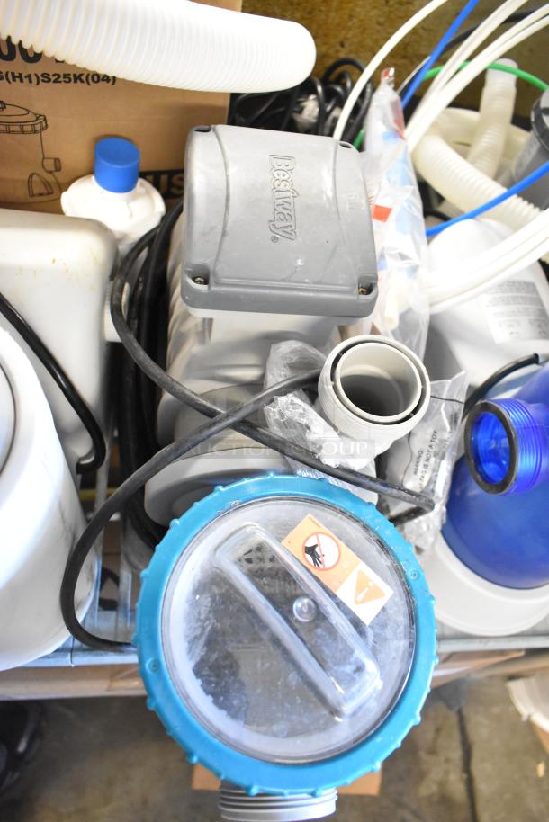 Assorted items including a Bestway filter pump, blue lid, visible hoses, and packaging. Some wear and signs of use.
