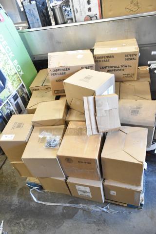 23 boxes of brand new scratch and dent center pull towel dispensers stacked on a pallet, various visible box labels.