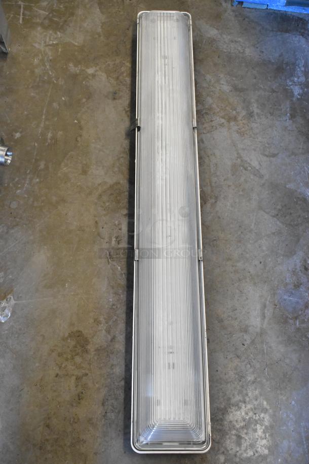 Rectangular industrial light fixture, metal frame, ribbed glass cover, in used condition. Auction includes four fixtures.