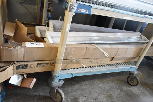 Seven light fixtures in original packaging on a metal cart. Condition appears new; visible tags show auction lot number 76.