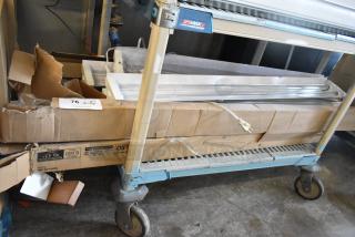 Seven light fixtures in original packaging on a metal cart. Condition appears new; visible tags show auction lot number 76.