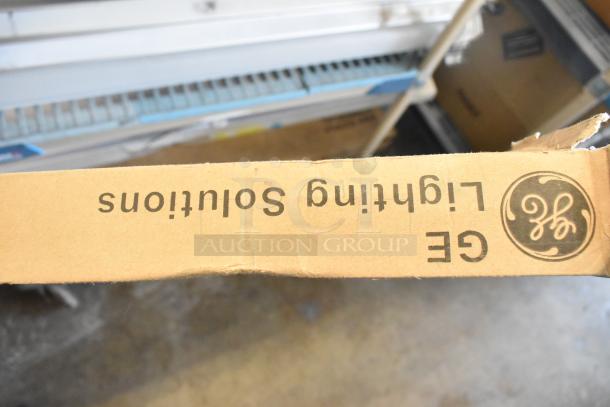 Cardboard box labeled "GE Lighting Solutions" containing various light fixtures, potentially new or gently used.